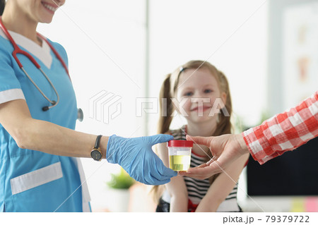 Mother giving doctor jar of urine in front of child at clinic closeup 79379722