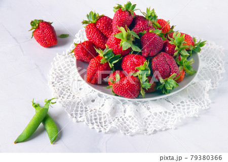 Fresh red strawberries and pods of green peas on white marble table. 79380366