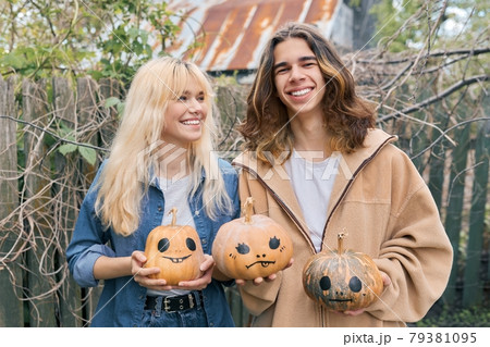 Couple of laughing teenagers with halloween pumpkins having fun 79381095