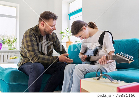 Father teaches his teenage son to play the electric guitar Father teaches his teenage son to play the electric guitar 79381160