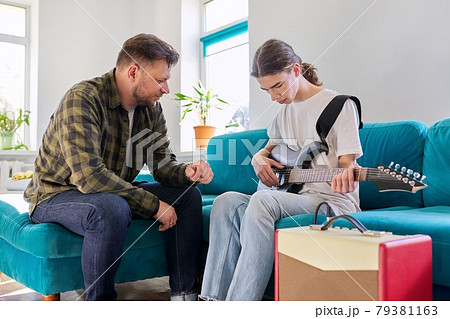 Father teaches his teenage son to play the electric guitar Father teaches his teenage son to play the electric guitar 79381163
