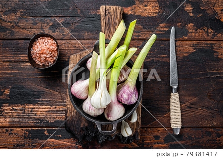 Young Spring garlic bulbs and cloves in a pan. Dark Wooden background. Top view 79381417