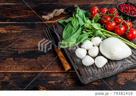 Mozzarella cheese, basil and tomato cherry on wooden board, Ingredients for Caprese salad. Dark wooden background. Top view. Copy space 79381419
