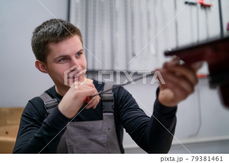 Portrait of concentrated young dent removing specialist on car repair station Portrait of concentrated young dent removing specialist on car repair station 79381461