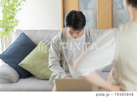 自宅のリビングで妻に叱られる夫 自宅のリビングで妻に叱られる夫 79385848