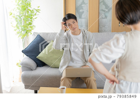 自宅のリビングで妻に叱られる夫 自宅のリビングで妻に叱られる夫 79385849