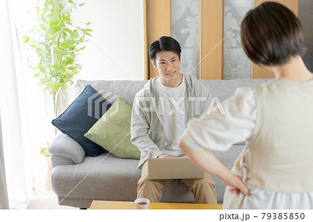 自宅のリビングで妻に叱られる夫 自宅のリビングで妻に叱られる夫 79385850