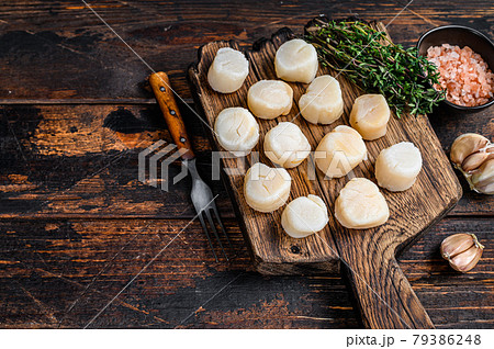 Steamed scallops meat on a wooden board. Dark wooden background. Top view. Copy space Steamed scallops meat on a wooden board. Dark wooden background. Top view. Copy space 79386248