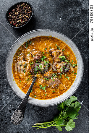 Lamb soup Kharcho with mutton meat, rice, tomatoes and spices in a bowl. Black background. Top view Lamb soup Kharcho with mutton meat, rice, tomatoes and spices in a bowl. Black background. Top view 79386303