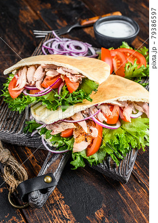 Greek gyros wrapped in pita breads with vegetables and sauce. Dark wooden background. Top view Greek gyros wrapped in pita breads with vegetables and sauce. Dark wooden background. Top view 79386597