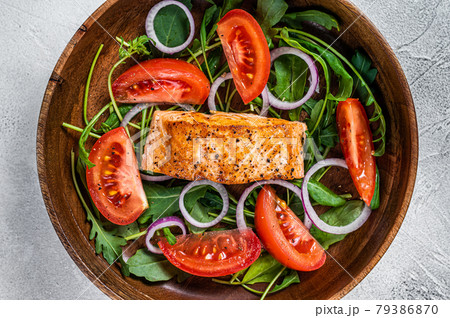 Salmon fillet steak salad with green leaves arugula, avocado and tomato in a wooden plate. White background. Top view Salmon fillet steak salad with green leaves arugula, avocado and tomato in a wooden plate. White background. Top view 79386870