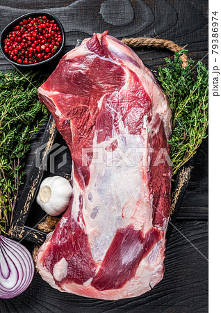 Fresh Raw lamb mutton shoulder meat in a wooden tray with thyme. Black wooden background. Top view 79386974