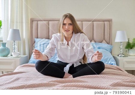 Serious anxious worried young woman sitting at home in bed 79390041