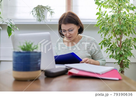 Female teacher teaching online, sitting at home at table with laptop Female teacher teaching online, sitting at home at table with laptop 79390636