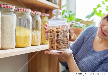 Home pantry kitchen interior, woman holding jar of almonds 79391633