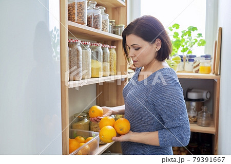Home pantry kitchen interior, woman holding oranges in hands, food storage 79391667