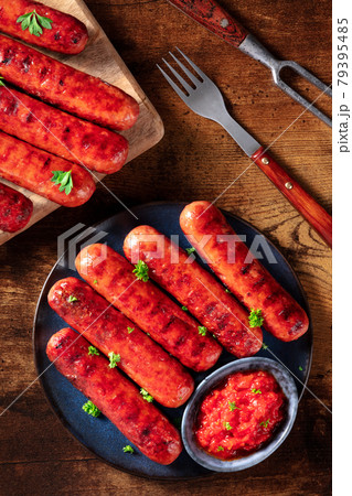 Sausages with ketchup, shot from the top on a dark rustic wooden table 79395485