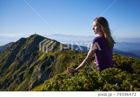 Charming young woman meditating in mountains. 79396472