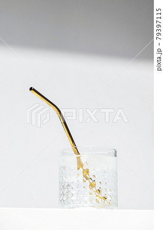 Transparent glass of water with reusable metal eco straw in sunlight. 79397115