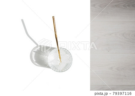 Transparent glass of water with reusable metal eco straw in sunlight with shadows. 79397116