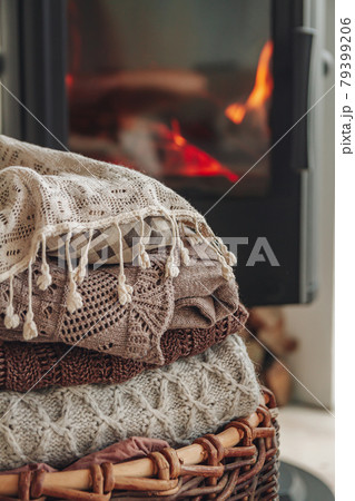A stack of warm clothes in a wicker basket an iron fireplace wit 79399206