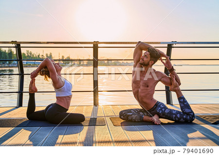 Couple doing practicing yoga together on nature outdoors . Morning exercises at the sunrise. Couple doing practicing yoga together on nature outdoors . Morning exercises at the sunrise. 79401690
