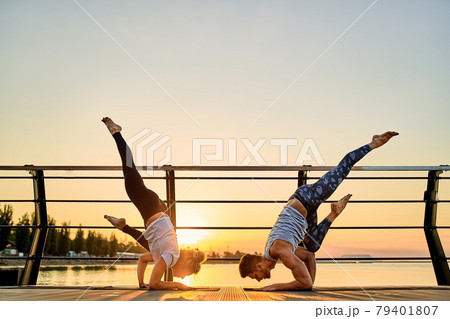 Couple doing practicing yoga together on nature outdoors . Morning exercises at the sunrise. Couple doing practicing yoga together on nature outdoors . Morning exercises at the sunrise. 79401807