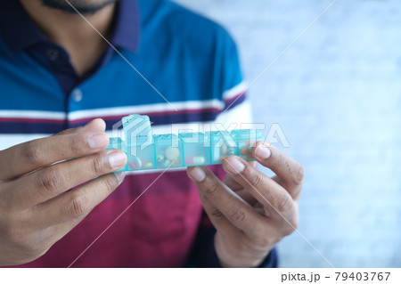 man's hands taking medicine from a pill box  79403767
