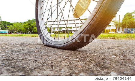 An old vintage style bicycle that has its back flat tire parking at the parking area An old vintage style bicycle that has its back flat tire parking at the parking area 79404144