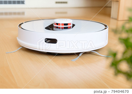 Robot vacuum cleaner performs cleaning of the room on the wooden floor. 79404670