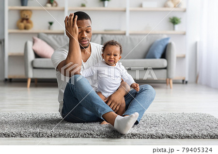 Exhausted Black Father Sitting With Crying Newborn Baby On Floor At Home 79405324