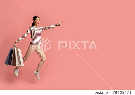 Shocking Sales. Excited Asian Woman Jumping With Shopping Bags And Pointing Aside Shocking Sales. Excited Asian Woman Jumping With Shopping Bags And Pointing Aside 79405471