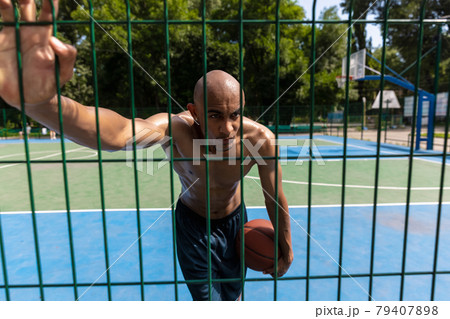Young strong man, male basketball player practicing at street public stadium, sport court or palyground outdoors. Concept of healthy active lifestyle, motion, hobby. 79407898