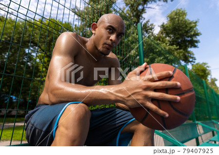 Young strong man, male basketball player practicing at street public stadium, sport court or palyground outdoors. Concept of healthy active lifestyle, motion, hobby. 79407925