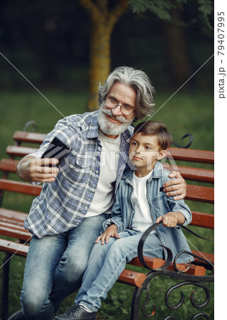Grandfather with grandchild sitting in a summer park Grandfather with grandchild sitting in a summer park 79407995