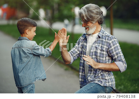 Grandfather with grandchild walking in a summer park Grandfather with grandchild walking in a summer park 79408138