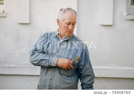 Old man standing near building with a repair tools 79408760