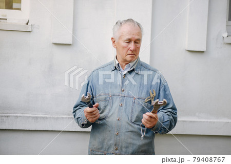 Old man standing near building with a repair tools 79408767