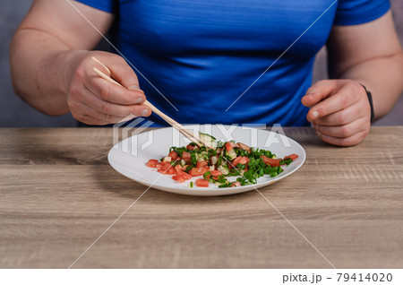 Salad with cucumber, tomato and green onions on a plate. A man holding a plate of salad 79414020
