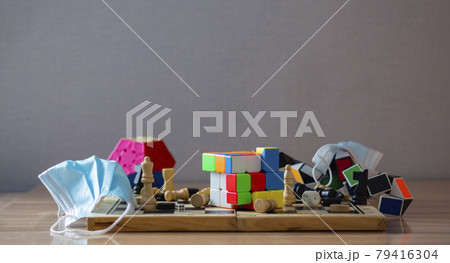 The concept of spending time during quarantine. On the table is a chessboard with a Rubik's cube, chess pieces, dice, medical masks, puzzles. 79416304