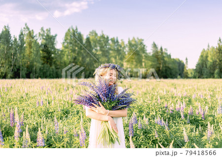 A hippy girl holding bouquet of wildflowers in her hands. Girl hid her face behind bouquet of lupins A hippy girl holding bouquet of wildflowers in her hands. Girl hid her face behind bouquet of lupins 79418566