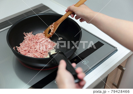 IHクッキングヒーターの上でフライパンを持って料理する主婦の女性 IHクッキングヒーターの上でフライパンを持って料理する主婦の女性 79428466