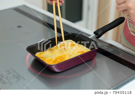 IHクッキングヒーターの上で卵焼きを作る主婦の女性 IHクッキングヒーターの上で卵焼きを作る主婦の女性 79430118