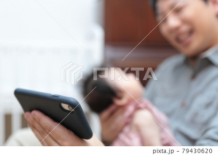 新生児を抱っこしてスマホ育児をするパパ 新生児を抱っこしてスマホ育児をするパパ 79430620