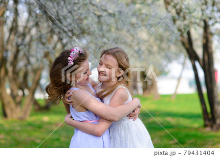 Young girls with blue eyes in white dresses in garden with apple trees blosoming 79431404