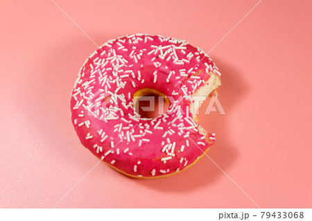 Bitten tasty pink donut on pink background. Top view Bitten tasty pink donut on pink background. Top view 79433068