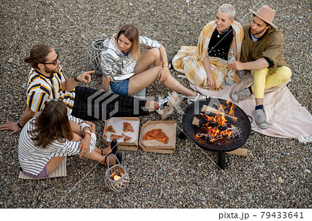 Friends sitting by the fireplace outdoors 79433641