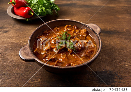 Traditional goulash meat in ceramic bowl with pepper and herbs Traditional goulash meat in ceramic bowl with pepper and herbs 79435483