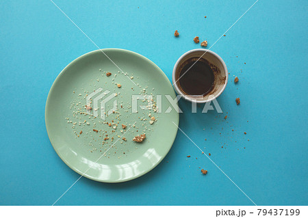 Empty plate with fork and crumbs and coffee cup after eating on blue background. 79437199