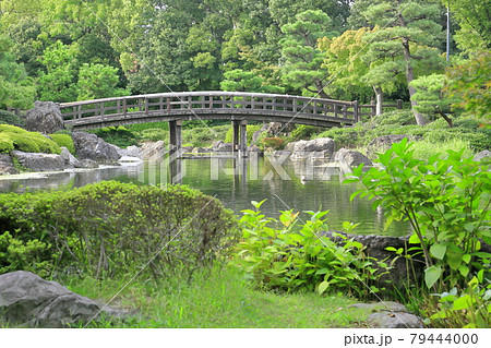 新緑と木製橋が池に映る日本庭園の風景 79444000